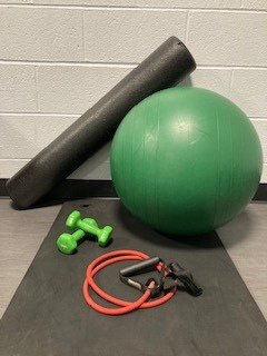 Balance ball, hand weights, elastic band with handles, foam roller on an exercise mat